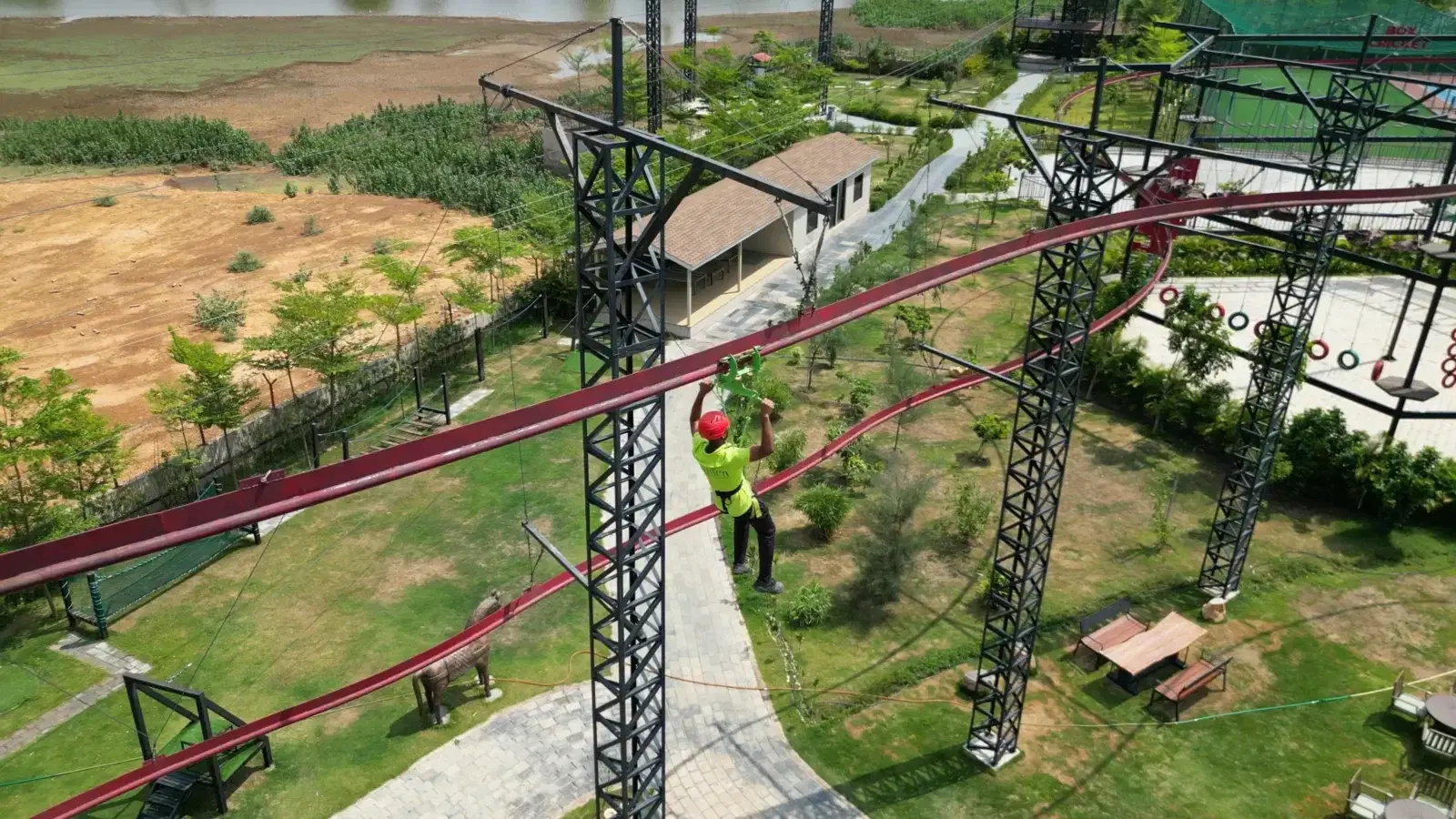 Roller coaster zipline track curving through the Maira Resort park, aerial view