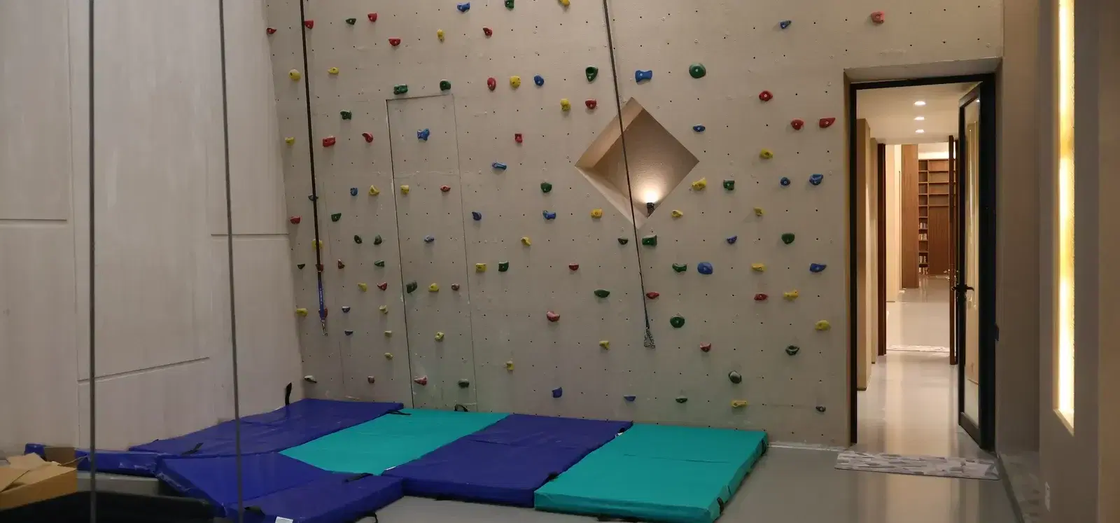 Base of the designer climbing wall with crash mats inside the residence